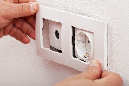Male hands changing an electical wall outlet Male electrician hands changing an electical wall outlet or socket - closeup